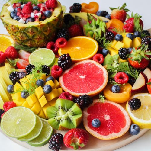 A vibrant fruit platter featuring citrus fruits, berries, kiwi, and pineapple.