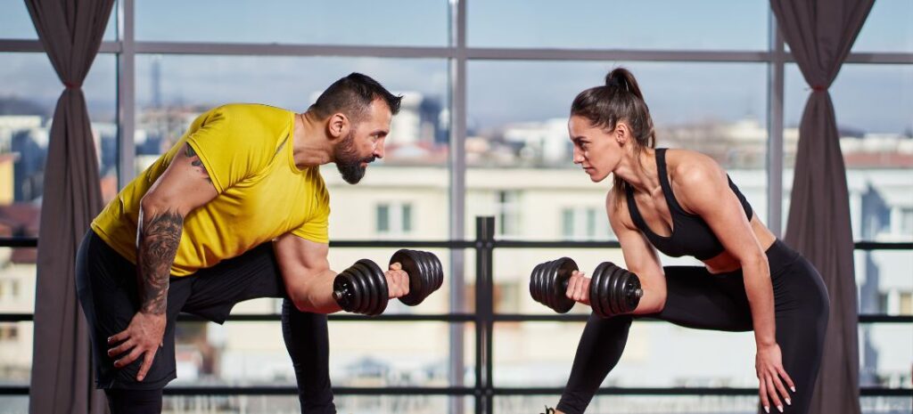 A man and a woman training together with dumbbells as a way to gain weight.
