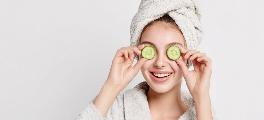 Smiling woman with cucumber slices on eyes, bathrobe, spa treatment, dark circles, teeth whitening